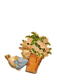Ceramic figurine of a sleeping bunny in a blue outfit, leaning against a flower pot with pink flowers and green leaves, detailed and colorful.
