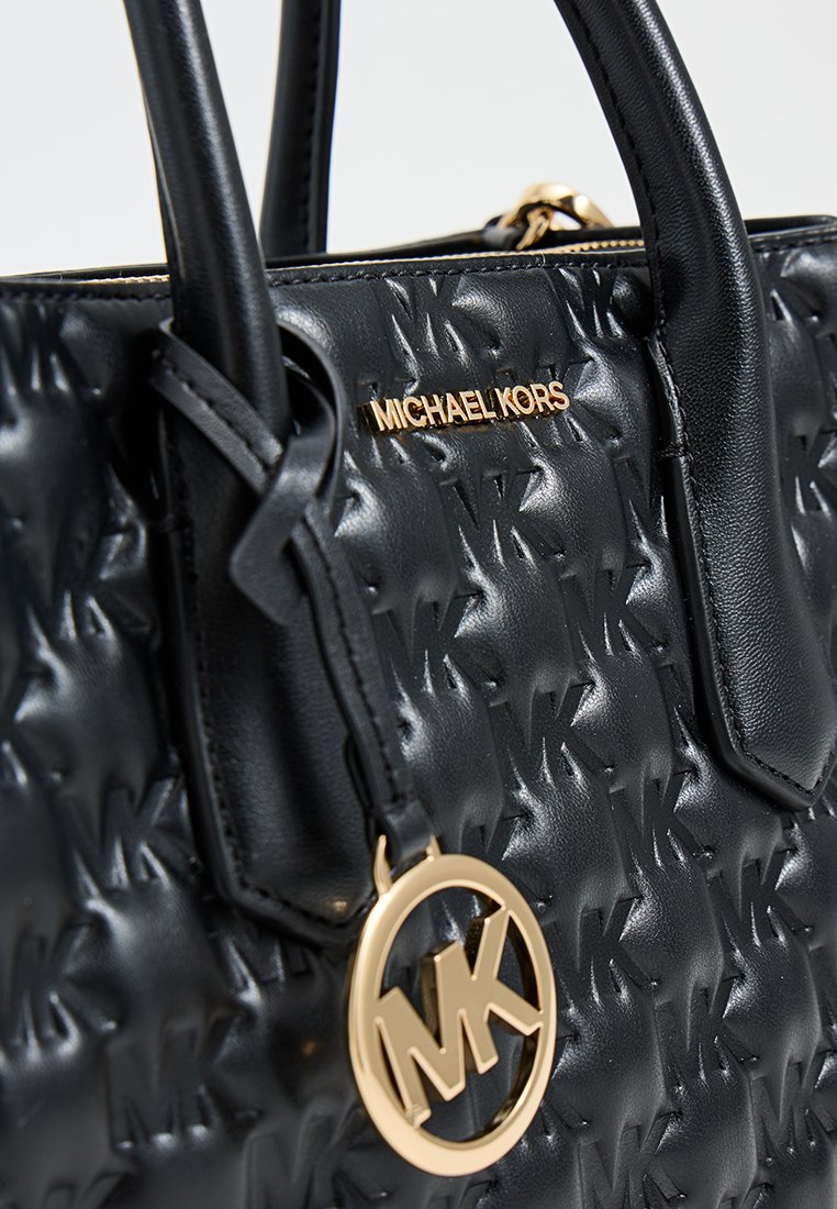 Sac à main noir avec motif de logo en relief, texture lisse, accessoires en or et un pendentif logo circulaire. Dispose de poignées doubles pour le transport.
