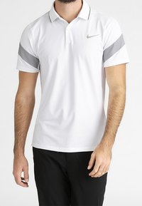 Bílá polo tričko Nike s šedými akcenty na rukávech, s knoflíkovým límečkem, krátkými rukávy a malým logem na hrudi.