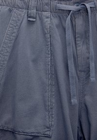 Gray shorts made of textured fabric, featuring an elastic waistband with a drawstring and stitched detailing on the side seam pockets.