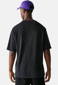 Schwarzes Baumwoll-T-Shirt mit kurzen Ärmeln und lockerer Passform. Mit Rundhalsausschnitt und nahtlosem Schulterdesign. Strukturierter, lässiger Look.