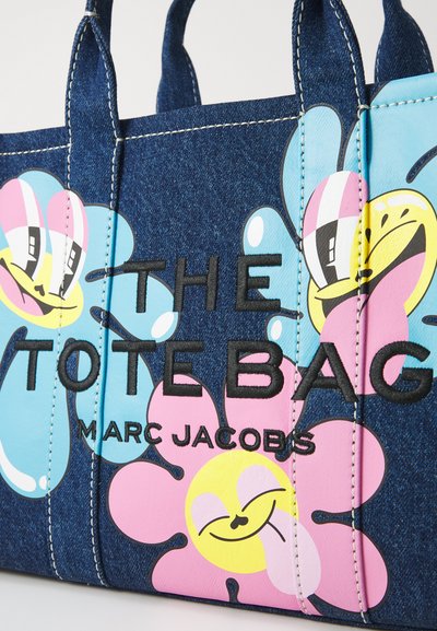 Denimová taška s barevnými květinovými vzory v růžové, žluté a modré. Na přední straně je černý text "THE TOTE BAG" a "MARC JACOBS".