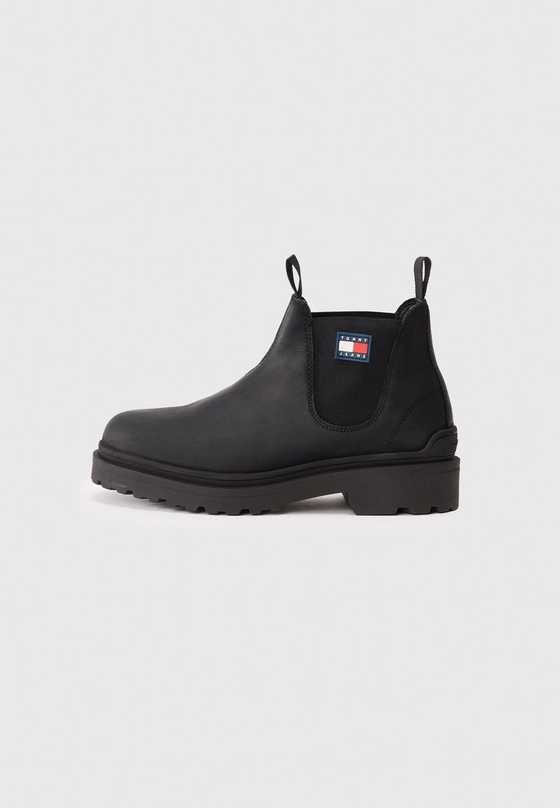 Bottine Chelsea en cuir noir avec languettes de tirage, panneaux latéraux élastiques, semelle robuste et petit logo Tommy Jeans sur le panneau latéral.