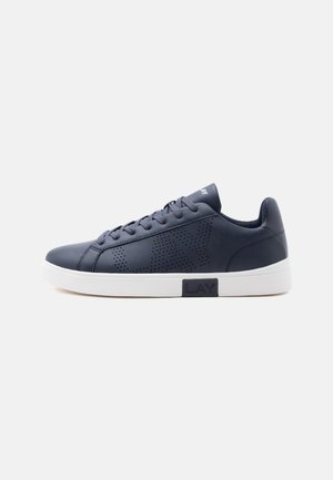 Sneaker bassa blu scuro con dettaglio laterale traforato e suola bianca con etichetta nera "LAY" su uno sfondo chiaro semplice.