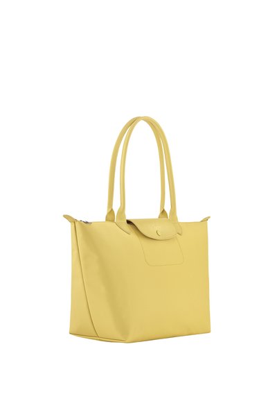 Yellow tote bag with long handles, a top flap with snap button, and a zipper closure on top, shown on a white background.