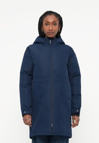 Parka blu navy con cappuccio, due tasche frontali, chiusura frontale con zip e polsini regolabili. Realizzata in un materiale liscio e isolante.