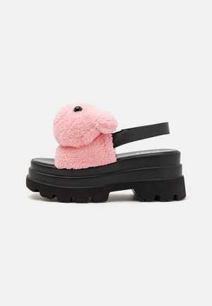 Stevige zwarte plateauzandalen met een roze, harig teddyberenhoofd aan de voorkant en een zwarte enkelband.