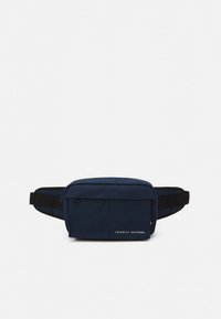 Marsupio blu navy con tasca frontale, tracolla regolabile nera e piccolo logo Tommy Hilfiger sul lato anteriore inferiore destro.
