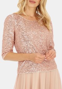 Różowa złota bluzka z cekinami, z rękawami o długości trzy czwarte, okrągłym dekoltem, rozciągliwym dzianinowym materiałem i teksturowanym wykończeniem, w połączeniu z luźną spódnicą.