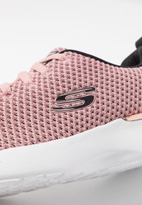 Rosa nät sneakers med vit sula, rund tå och svarta detaljer. Märkbar glänsande logotyp på sidan och texturerad övre yta.