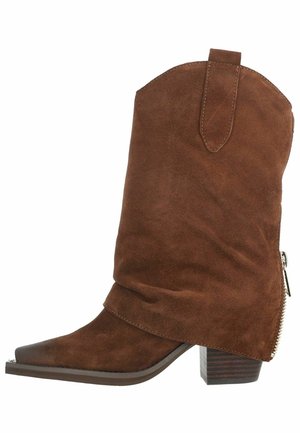 Botte western mi-mollet en daim brun avec bout pointu, talon bloc en bois, languette de tirage et détail de fermeture éclair latérale.