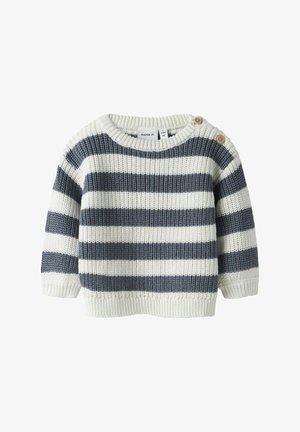 Striped sweater in cream and navy blue, knitted texture, round collar, short sleeves, featuring two wooden buttons on the shoulder.