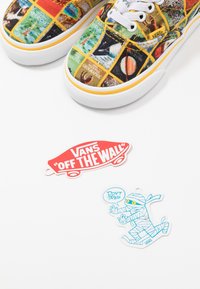 Baskets Vans colorées avec des impressions de couvertures de National Geographic, accompagnées du logo skateboard Vans "Off The Wall" et d'une momie dessin animé disant "Don't Trip."