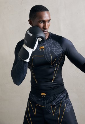 Black long-sleeve athletic shirt with snake pattern and yellow accents. Black shorts with similar design. Model wearing black boxing gloves.