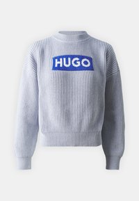 Lichtgrijze geribbeld gebreide trui met lange mouwen en "HUGO" in witte letters op een blauwe rechthoekige patch op de borst.
