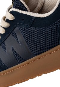 Sneaker blu navy con materiali in rete e suede, lacci crema e suola in gomma color beige. Presenta un accento del logo sul lato.