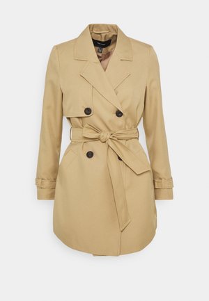 Beige trenchcoat met dubbele rij knopen, ceintuur in de taille en klepzakken. Heeft brede revers en verstelbare mouwriempjes.