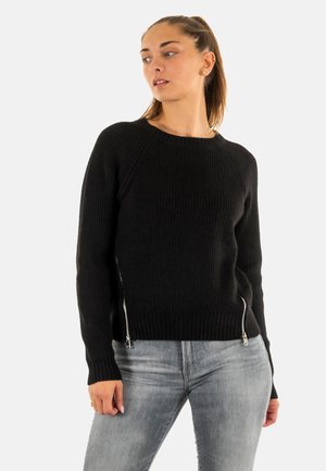 Pull noir côtelé à manches longues, col rond, avec des accents de fermeture éclair argentés sur les côtés. Fabriqué à partir d'un tissu tricoté texturé.