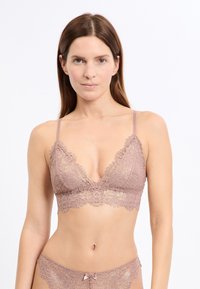 Koronkowy biustonosz typu bralette w miękkim odcieniu malwy, z głębokim dekoltem w kształcie litery V, falistymi brzegami, cienkimi regulowanymi ramiączkami oraz kwiatowym wzorem z połyskiem.