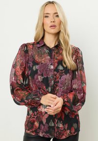 Schwarze Bluse mit floralen Mustern in verschiedenen Farben, ausgestattet mit einer knöpfbaren Front, Puffärmeln und einem semi-transparenten Stoff mit strukturiertem Muster.