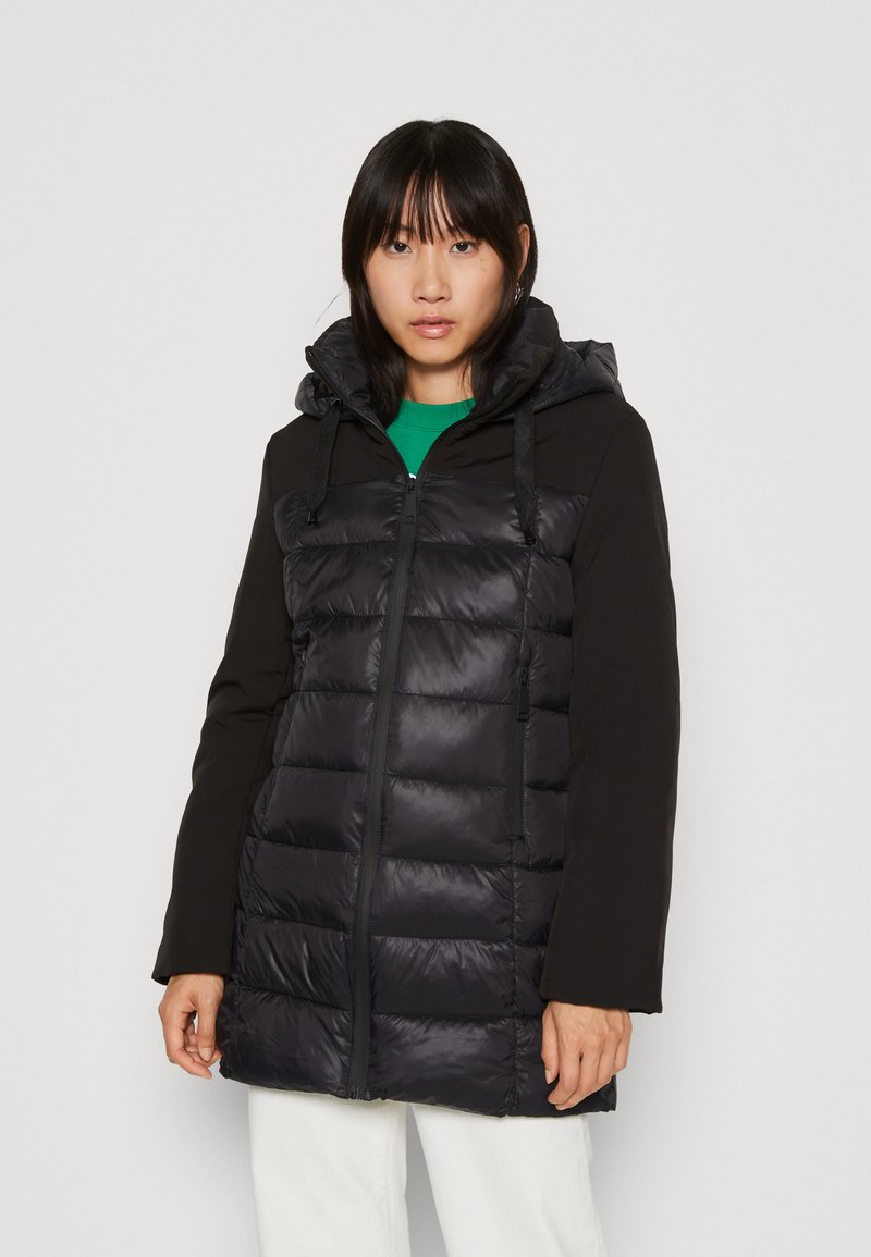 Veste rembourrée noire avec capuche, fermeture éclair à l'avant et tissu contrastant sur les manches. Dotée d'une texture matelassée et de cordons de serrage ajustables.