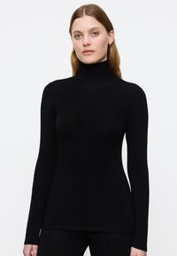 Maglietta nera a maniche lunghe con colletto alto realizzata in materiale morbido, caratterizzata da un design aderente e una texture liscia, con un collo alto per una copertura aggiuntiva.