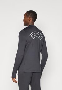 Γκρι αθλητική μπλούζα με μακριά μανίκια που διαθέτει καμπύλη γραφική παράσταση "PARIS" στο πίσω μέρος, κατασκευασμένη από ελαφρύ υλικό με εφαρμοστή σχεδίαση.