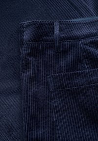 Marinblå kordflorsbyxor med vertikal ribbad struktur, med standard midja och fickdetaljer. Matt yta med mjuk känsla.
