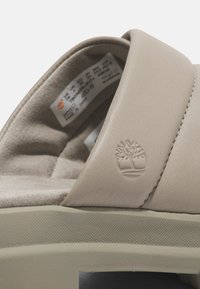 Infradito beige chiaro realizzati in pelle liscia con suola in gomma testurizzata. Presentano logo impresso e dettagli di cucitura discreti.
