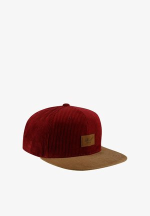 Red corduroy cap with a brown suede visor, featuring a rectangular leather patch on the front. Textured fabric and detailed stitching.