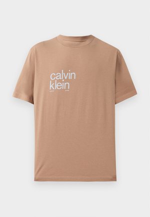 Majica kratkih rukava od svijetloplavog pamučnog materijala, s velikim bijelim natpisom "calvin klein" na prednjoj strani i dizajnom okruglog izreza.
