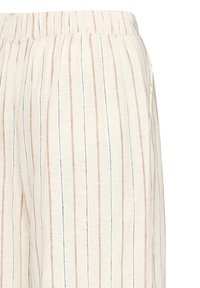 Pantalon beige avec fines rayures verticales rouges et noires, taille élastique, et poche latérale visible sur le côté droit.