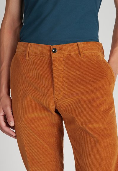 Spodnie z korduroy w ciepłym pomarańczowo-brązowym kolorze. Posiadają pionowe żeberka, zapięcie na guzik oraz przednie kieszenie. Tkany materiał.