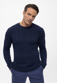 Tumed sinise värvi kabeli kootud sviiter, millel on ümar kaelus ning soonikud varrukaotstes ja allservas, kantud koos hästitikandud siniste pükste kanssa. Tekstuuriga muster üle kogu.