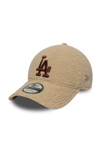 Beige gestructureerde baseballpet met een bruin LA-logo, gebogen rand, verstelbare strap en fuzzy materiaal voor warmte.