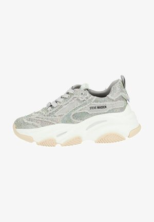 Silberner Sneaker mit einer strukturierten, glitzernden Oberseite, ausgestattet mit einer chunky weißen Sohle und grauen Akzenten. Schnürung vorne und Branding an der Seite.