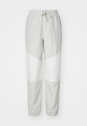 Világosszürke melegítőnadrág fehér átlós panelek szegélyezésével, rugalmassal készült derékkal, húzózsinórral, valamint rugalmas szegélyekkel a bokáknál. Sima, könnyű anyag.