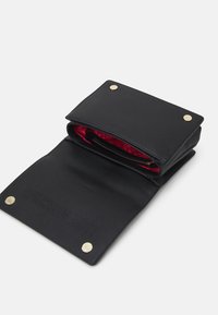 Svart läderplånbok med strukturerad yta, med ett röd mönstrad foder, en dragkedjeficka och guldfärgade tryckknappar.