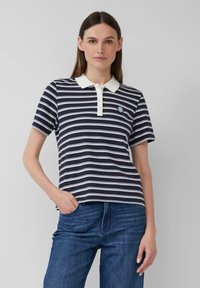 Marineblauwe en witte gestreepte polo met een witte kraag, korte mouwen en een rond logo op de linkerborst. Zachte stof met een klassieke pasvorm.