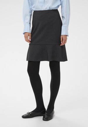 Jupe grise évasée en tissu au toucher lisse, associée à des collants noirs et des chaussures plates noires, dotée d'un léger volant au bas.