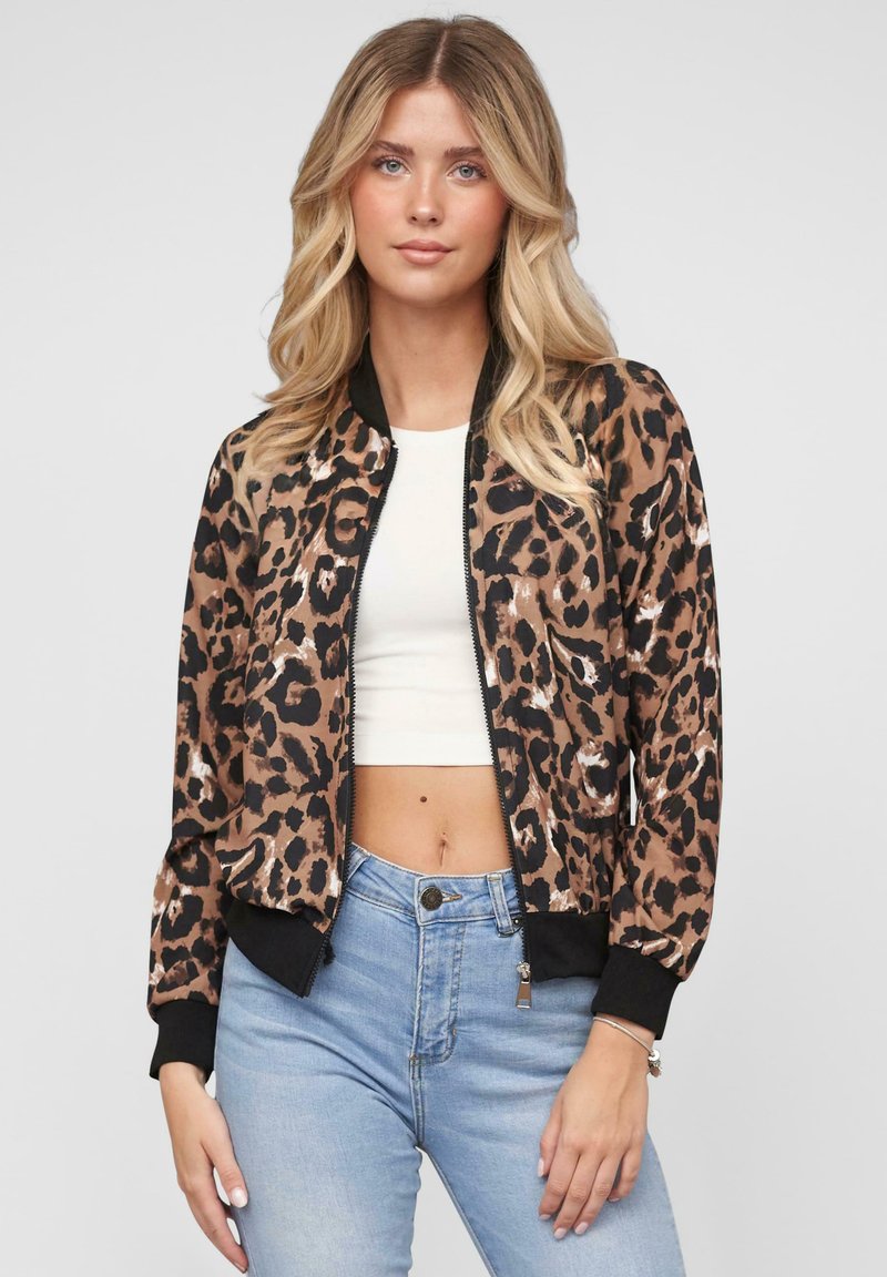 Giubbotto bomber con stampa leopardata in marrone e nero, design aderente, polsini e orlo a costine, chiusura con zip, indossato sopra un crop top bianco.