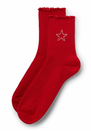 Calze rosse a costine con orlo arricciato e un design di stelle argento adornate con strass sul lato esterno. Texture liscia.