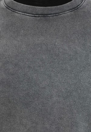 Sweatshirt gris avec un col rond côtelé, fabriqué en tissu doux et texturé, présentant une couleur uniforme et des variations subtiles de ton.