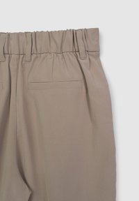 Beige Hose mit einem gesammelten elastischen Bund, glatter Textur, zwei Gesäßtaschen und Gürtelschlaufen am Bund.