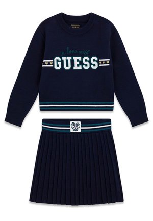 Marineblå langærmet sweater med teksten "in love with GUESS" og matchende plisseret nederdel med stribet taljebånd og GUESS-logo patch.