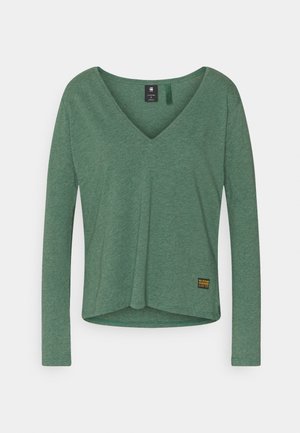 Groen shirt met lange mouwen en V-hals met een klein rechthoekig merklabel vlak bij de onderzoom op een witte achtergrond.