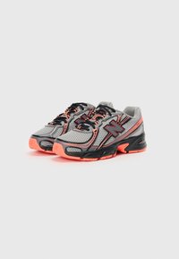 Chaussures de course légères en mailles grises avec des accents noirs et une semelle néon orange, présentant une tige texturée et un design à lacets.