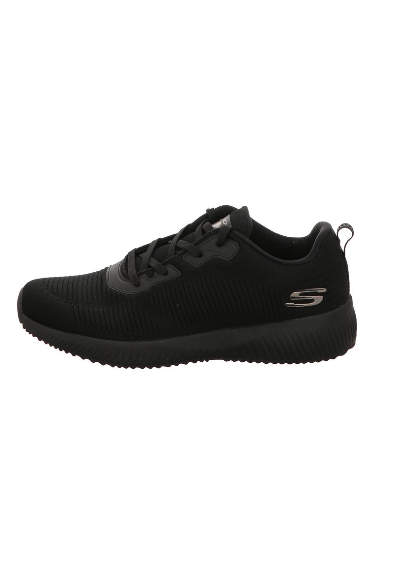 Scarpa sportiva nera con texture a coste, design con lacci e linguetta. Presenta un prominente logo 'S' sul lato. Suola in gomma.