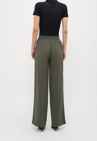 Olive green wide-leg pants with an elastic waistband, paired with a fitted black short-sleeve top. Smooth texture, minimal design.