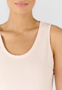 Canottiera rosa chiaro con scollatura ondulata, realizzata in un tessuto morbido ed elastico. Le spalline regolabili si adattano comodamente alle spalle.